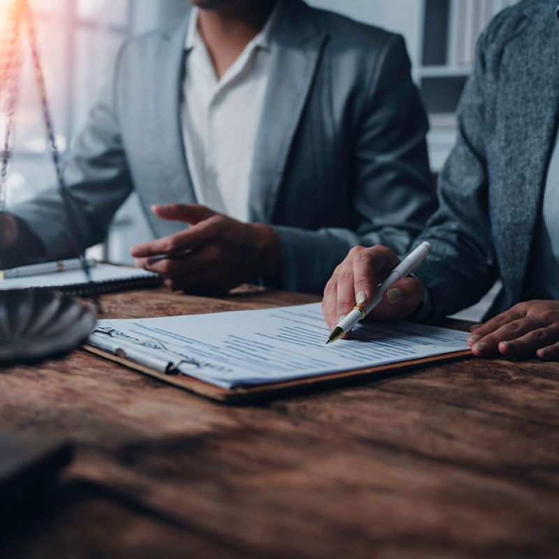 Two professionals reviewing legal documents at a desk, symbolizing business or legal consultation.