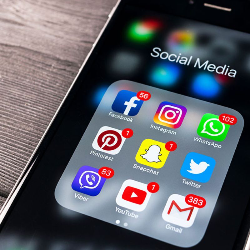 Smartphone displaying social media app icons with notification badges, including Facebook, Instagram, and WhatsApp.