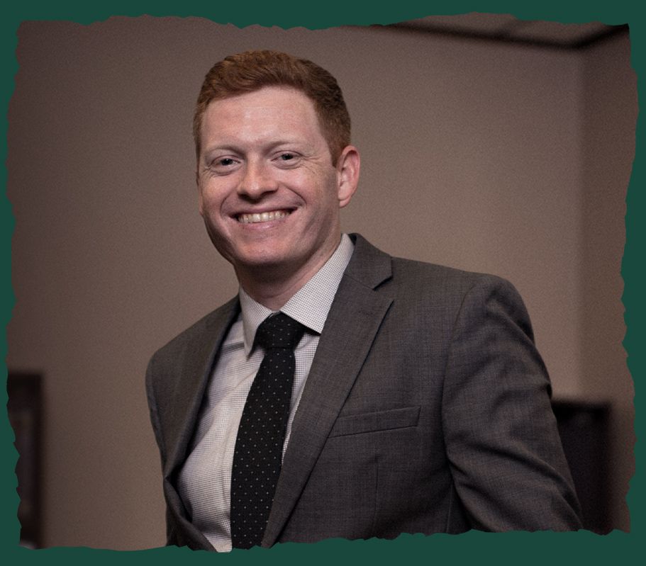 A smiling man in a suit and tie in a professional setting.