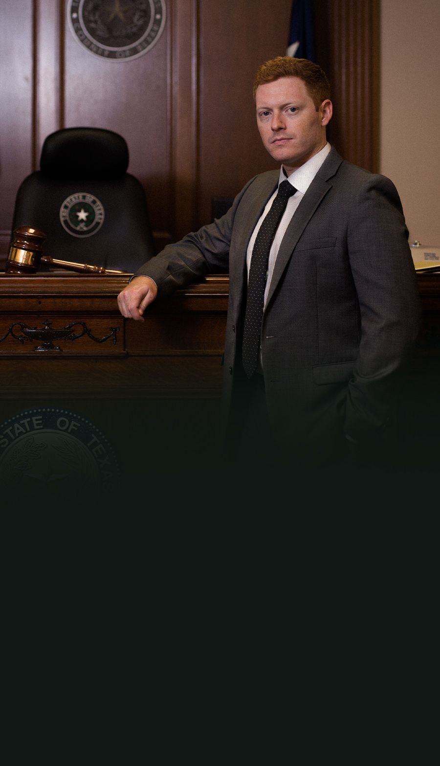Man in a suit stands confidently in a Texas courtroom with a gavel, symbolizing justice and authority.