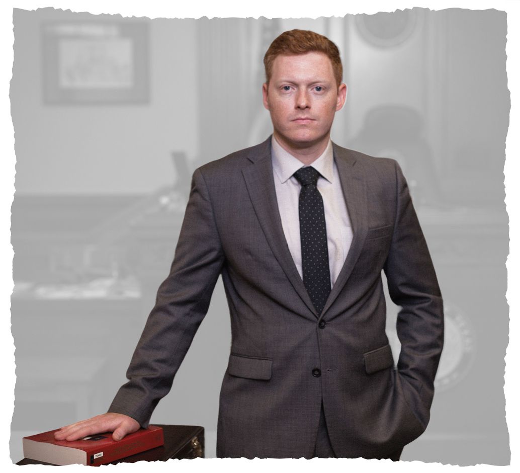 Professional male in a suit stands confidently with a hand on a legal book, symbolizing authority in a courtroom.