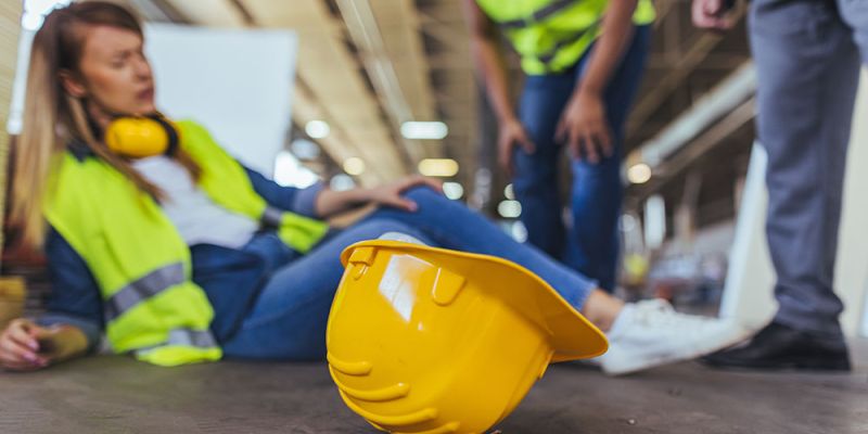 Construction worker injured on site, hard hat foreground, safety accident concept.
