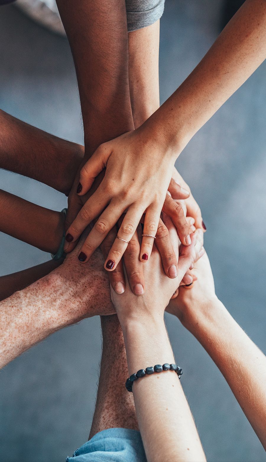 Diverse group of hands stacked together, symbolizing teamwork and unity in a collaborative environment.