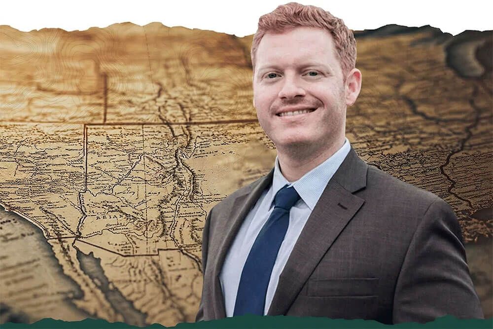 Will Clark in a suit in front of a vintage map background, conveying exploration and professional success.