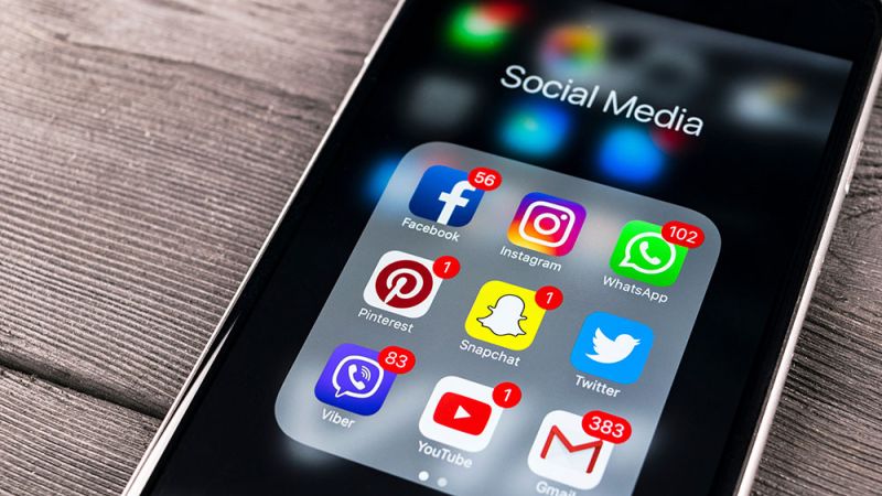 Smartphone displaying social media app icons with notification badges, including Facebook, Instagram, and WhatsApp.