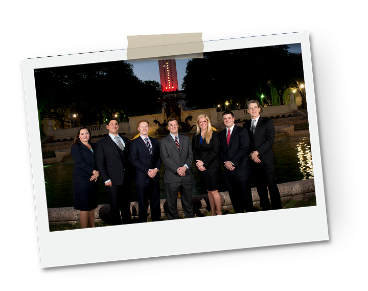 A group of professionals in formal attire standing in front of a lit tower at night.