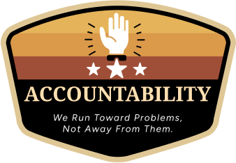 A badge featuring a raised hand above three stars, set against a striped background. Text reads: "ACCOUNTABILITY - We Run Toward Problems, Not Away From Them."