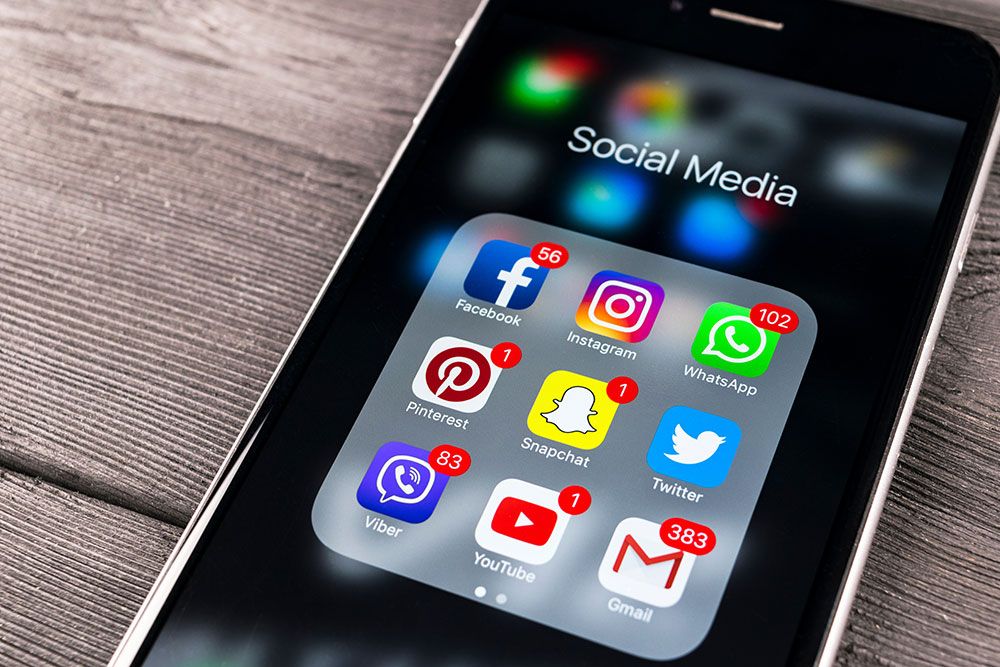 Smartphone displaying social media app icons with notification badges, including Facebook, Instagram, and WhatsApp.