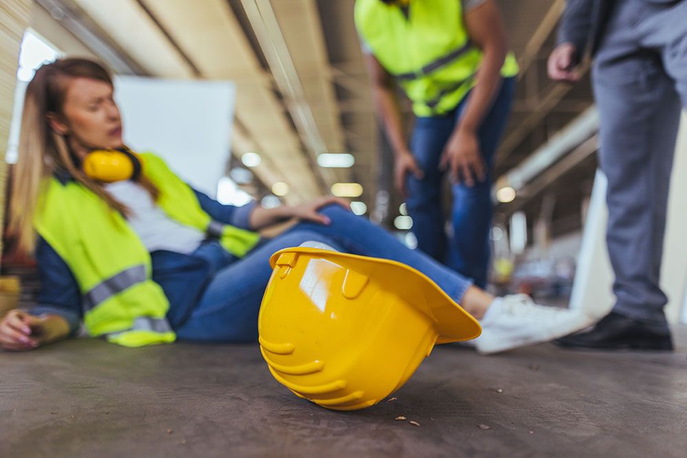 Construction worker injured on site, hard hat foreground, safety accident concept.
