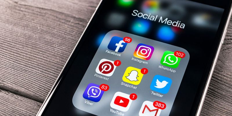 Smartphone displaying social media app icons with notification badges, including Facebook, Instagram, and WhatsApp.