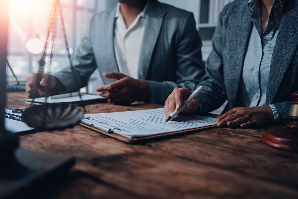 Two professionals reviewing legal documents at a desk, symbolizing business or legal consultation.