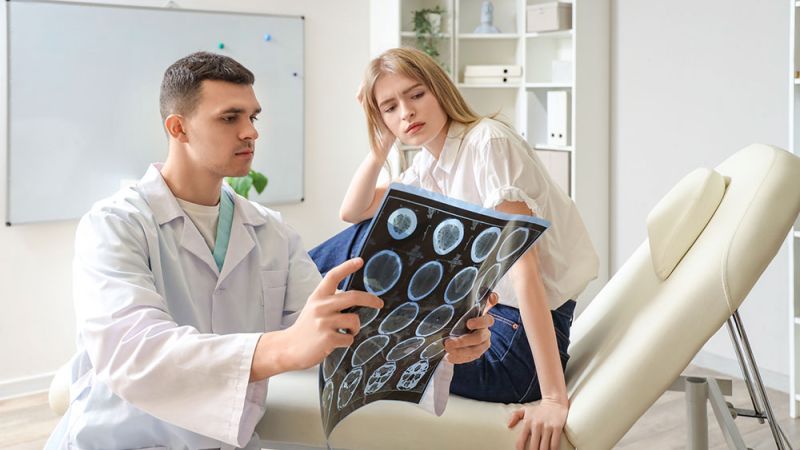 Doctor showing brain scan results to a concerned patient in a modern medical office.