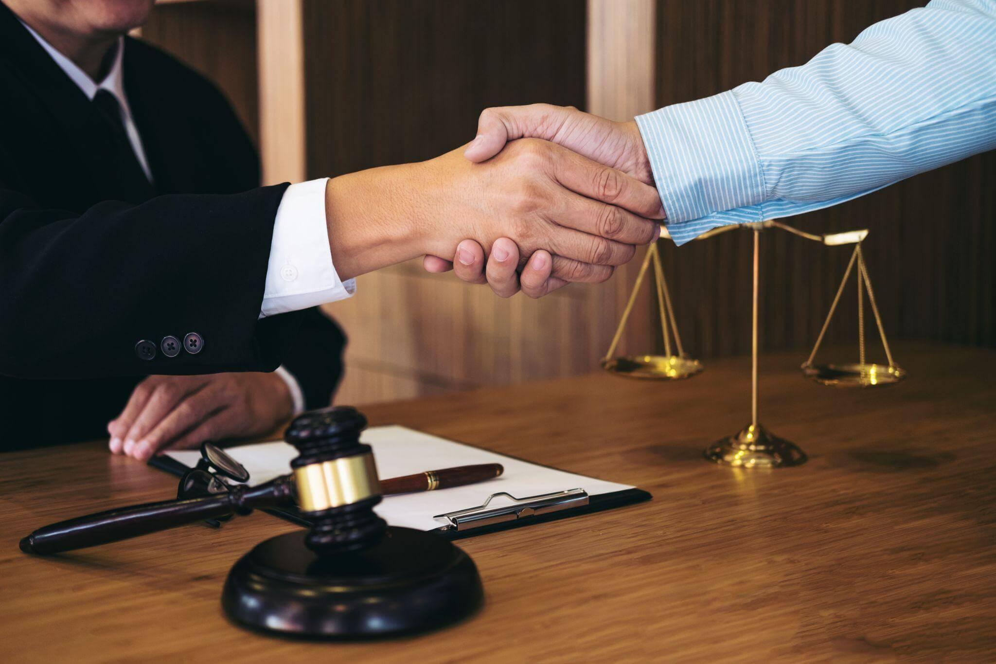 two people shaking hands in front of a scale of justice